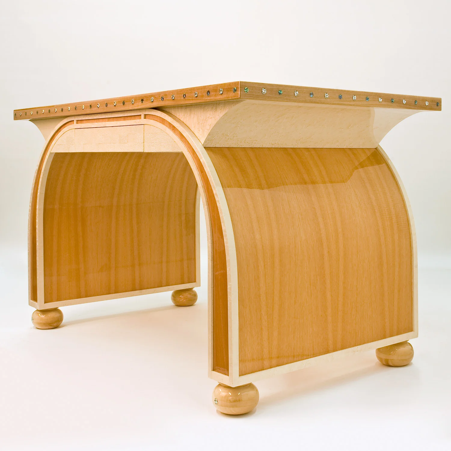 Curved custom furniture showcasing a refined wood finish and ornamental metal detailing.